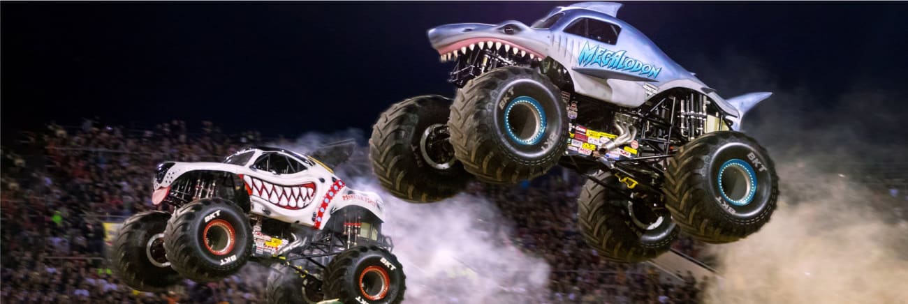 Deux camions de Monster Jam en plein saut au-dessus de la piste